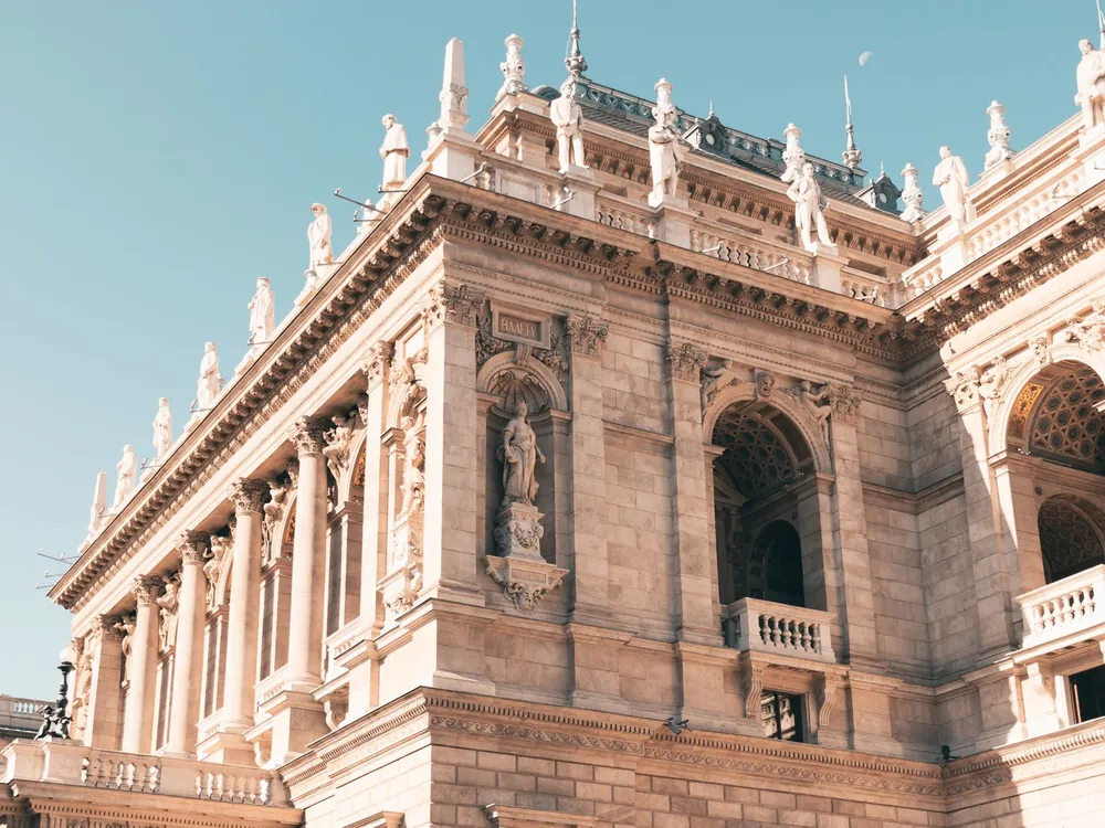 Statues along the roofline and a figure in a niche on the carved stone front of the Opera House
